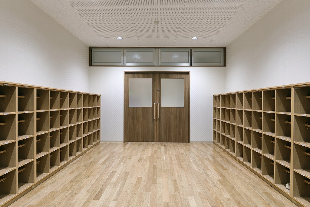 両側に木目調の収納靴箱が並ぶ、真愛三ツ谷こども園の明るく広々とした1階エントランス。